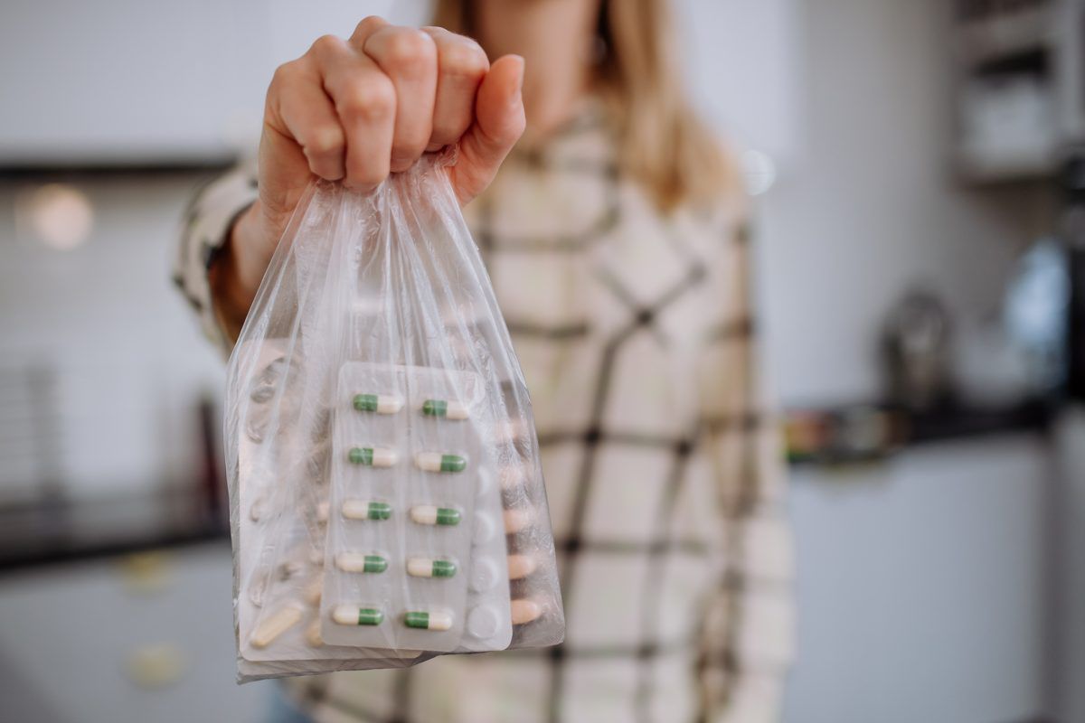 imagem com uma mulher segurando um saco de medicamentos